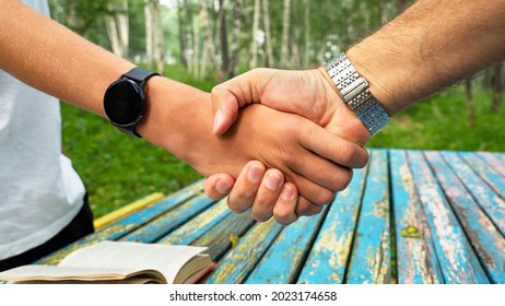 Handshake. An adult shakes hands with a child or teenager in approval - Shutterstock ID 2023174658