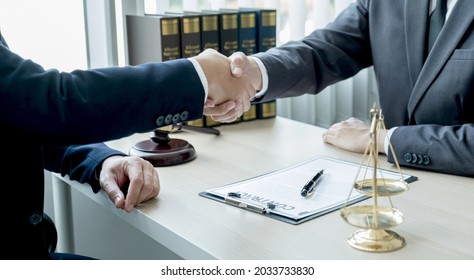 Handshake after Lawyer  providing legal consult business dispute service to the man at the office with justice scale and gavel hammer. - Shutterstock ID 2033733830
