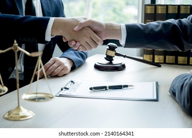 Handshake after Lawyer  providing legal consult business dispute service to the man at the office with justice scale and gavel hammer. - Shutterstock ID 2140164341