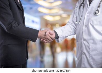Handshake between businessman and doctor with blur people in hospital lobby background  