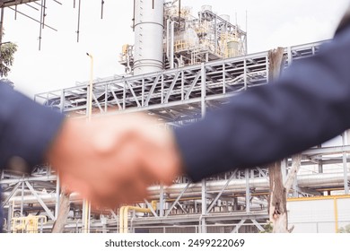 A handshake between two engineers against a background of an oil refinery, Focus background