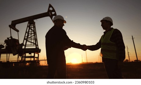 handshake business oil contract. handshake worker and businessman shaking hands against sunlight the backdrop of an oil pump. oil extraction business concept. silhouette handshake contract - Powered by Shutterstock