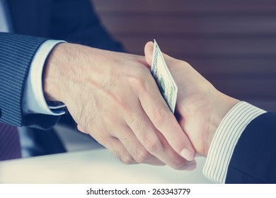 Handshake of businessmen with money, bribery concept - vintage tone