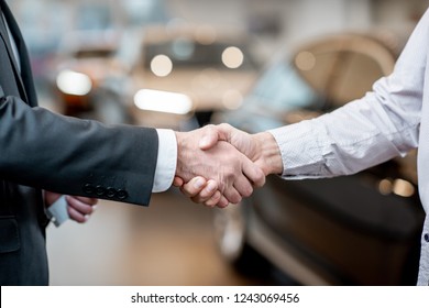 Handshake Of A Client And Salesperson At The Car Showroom. Close-up Vieww