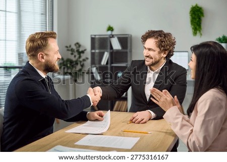 Handshake concludes interview and confirms hiring agreement. Recruiter and candidate smile in office as HR applauds, paperwork on table and positive vibe. Clear concept of hiring success.