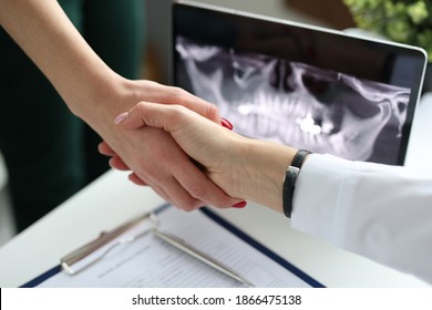 Handshake doctor dentist and patient near computed tomogram of jaw in clinic. Successfully completed dental implantation concept - Powered by Shutterstock