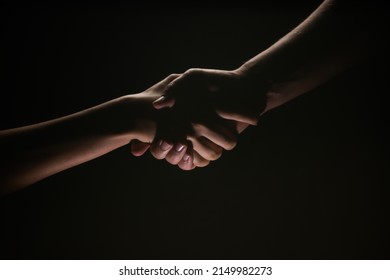 Handshake Hand, Arm On Salvation. Close Up Help Hand. Two Hands, Helping Arm Of A Friend, Teamwork. Rescue, Helping Gesture Or Hands, Agreement. Black Background.