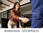 Handshake of happy young business woman and business man at office meeting. Female hr bank manager, financial advisor handshaking recruit, greeting client. Hiring at job interview, partnership concept