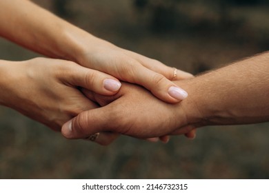 Handshake Of Husband And Wife. The Girl Holds The Guy's Hand With Both Hands. Love In An Embrace