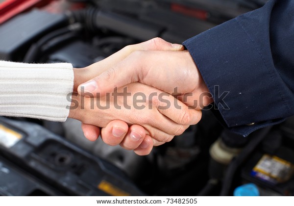 Handshake.\
Mechanic and client woman in auto repair\
shop.