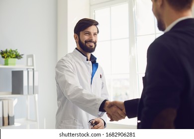 Handshake. Practicing doctor and patient shaking hands smiling at the clinic.