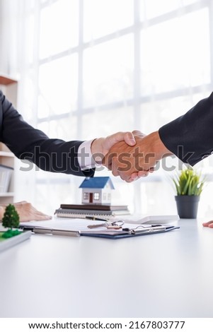 Handshake Real estate broker agent presenting and consult to customer to decision making sign insurance form agreement, buy and sell home model, concerning mortgage loan offer for and house insurance