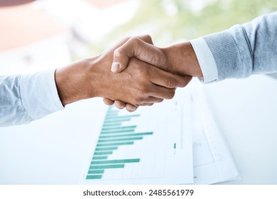 Handshake, teamwork and business people in office with paperwork for B2B deal, agreement or meeting. Above, graphs and employees shaking hands for partnership, collaboration or project data analytics - Powered by Shutterstock