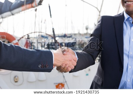 handshake of two businessmen near the yachts in the port