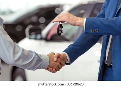 Handshake of two businessmen when selling a car in a motor show, close-up - Shutterstock ID 386720620