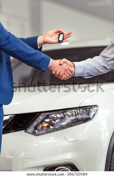 Handshake of two businessmen when selling a car\
in a motor show,\
close-up