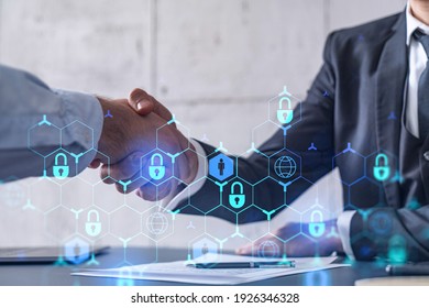 Handshake of two businessmen who enters into the contract to protect cyber security of international company. Padlock Hologram icons over the table with documents.