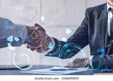 Handshake of two businessmen who enters into the contract to develop a new software to improve business service at a company. Technological icons over the table with the document. - Shutterstock ID 1968390493