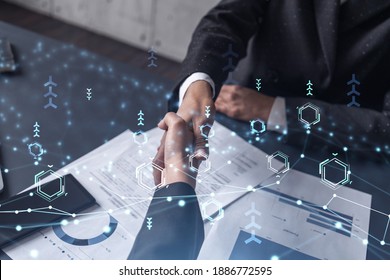 Handshake of two businesswomen who enters into the contract to develop a new software to improve business service at a company. Technological icons over the table with the document.