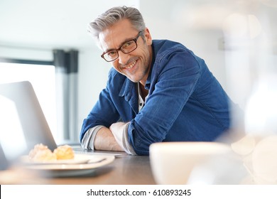 Handsome 45-year-old man at home connected on laptop