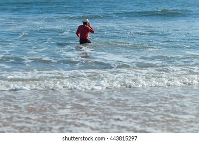 Handsome active man using smartphone, seaside background. Back side view