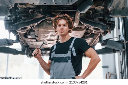 Handsome adult man in grey colored uniform standing below automobile. - Powered by Shutterstock