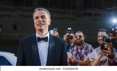 Handsome Adult Man In Tuxedo Standing On Red Carpet Of Luxury Event At Photographers And Fans