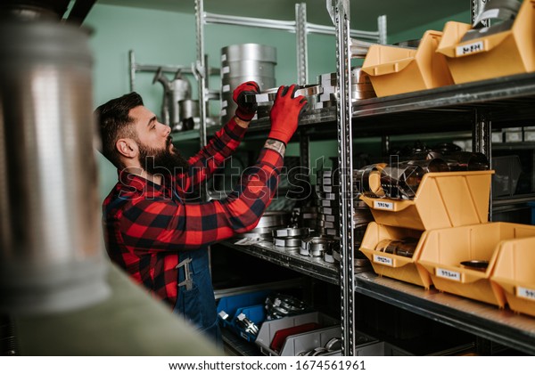 Handsome adult man working in car and truck spare parts warehouse. 