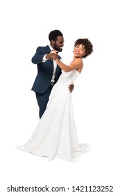 handsome african american bridegroom looking at happy bride while holding hands and dancing isolated on white 