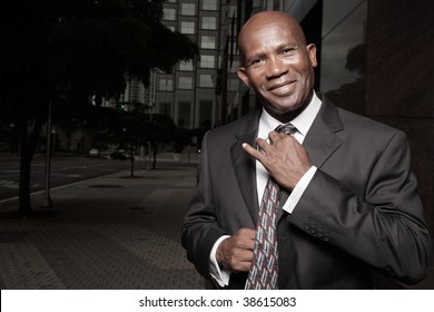 Handsome African American Businessman adjusting his tie and smiling - Powered by Shutterstock