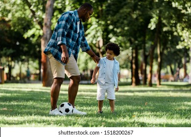 Handsome African American Father Playing Football With Cute Son 