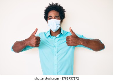 Handsome African American Man With Afro Hair Wearing Medical Mask Smiling With A Happy And Cool Smile On Face. Showing Teeth. 