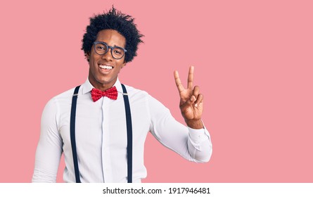 Handsome african american man with afro hair wearing hipster elegant look smiling with happy face winking at the camera doing victory sign. number two.  - Shutterstock ID 1917946481