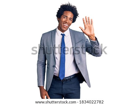 Handsome african american man with afro hair wearing business jacket waiving saying hello happy and smiling, friendly welcome gesture 