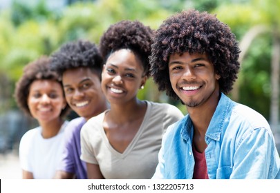 Handsome African American Man With Group Of Young Adults In Line Outdoor In City In Summer