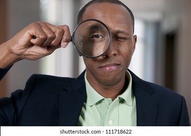 Handsome African American man looking through a large magnifying glass