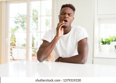 Handsome African American Man On White Table At Home Touching Mouth With Hand With Painful Expression Because Of Toothache Or Dental Illness On Teeth. Dentist Concept.