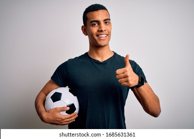 Handsome African American Man Playing Footbal Holding Soccer Ball Over White Background Doing Happy Thumbs Up Gesture With Hand. Approving Expression Looking At The Camera Showing Success.