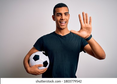 Handsome african american man playing footbal holding soccer ball over white background Waiving saying hello happy and smiling, friendly welcome gesture - Powered by Shutterstock