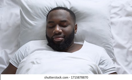 Handsome african american man sleeping in his cozy white bed, healthy sleeping - Shutterstock ID 1715878870