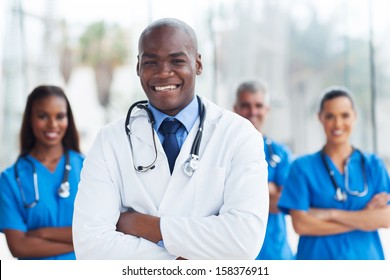 handsome african american medical doctor with colleagues in background