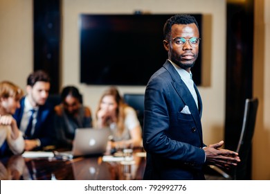 handsome african businessman looking on camera with group of businesspeople on background - Shutterstock ID 792992776