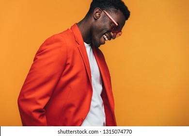 Handsome African Male Fashion Model With Sunglasses Smiling Against Orange Background. Stylish African Man Smiling In Studio.