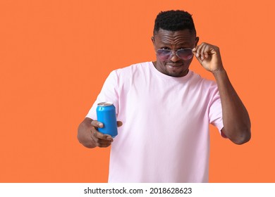 Handsome African-American man with soda on color background
