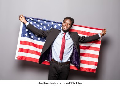 Handsome Afro American man in classic suit is smiling standing with American flag