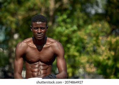 Handsome Afro American Runner Sitting On The Street While Taking Break After Training. Black Male Runner Having Rest After Workout