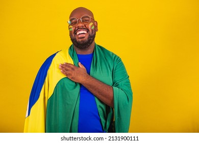 handsome afro brazilian man wearing glasses, brazilian fan, brazil, world cup 2022, hand to chest, singing anthem is born. Brazilian music. beloved homeland. patriot. - Powered by Shutterstock