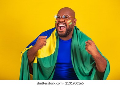 handsome afro brazilian man wearing glasses, brazilian fan, brazil, world cup 2022, clenched fists, screaming, cheering, vibrating, goal.