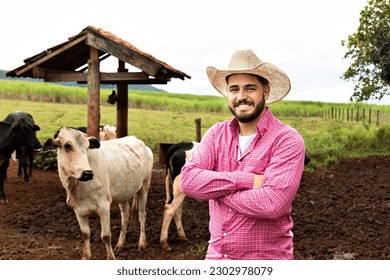 handsome agro man smiling looking at camera with arms crossed wearing hat in meadow