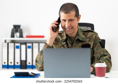 Handsome American soldier behind his computer talking on the phone at office - Shutterstock ID 2254702565